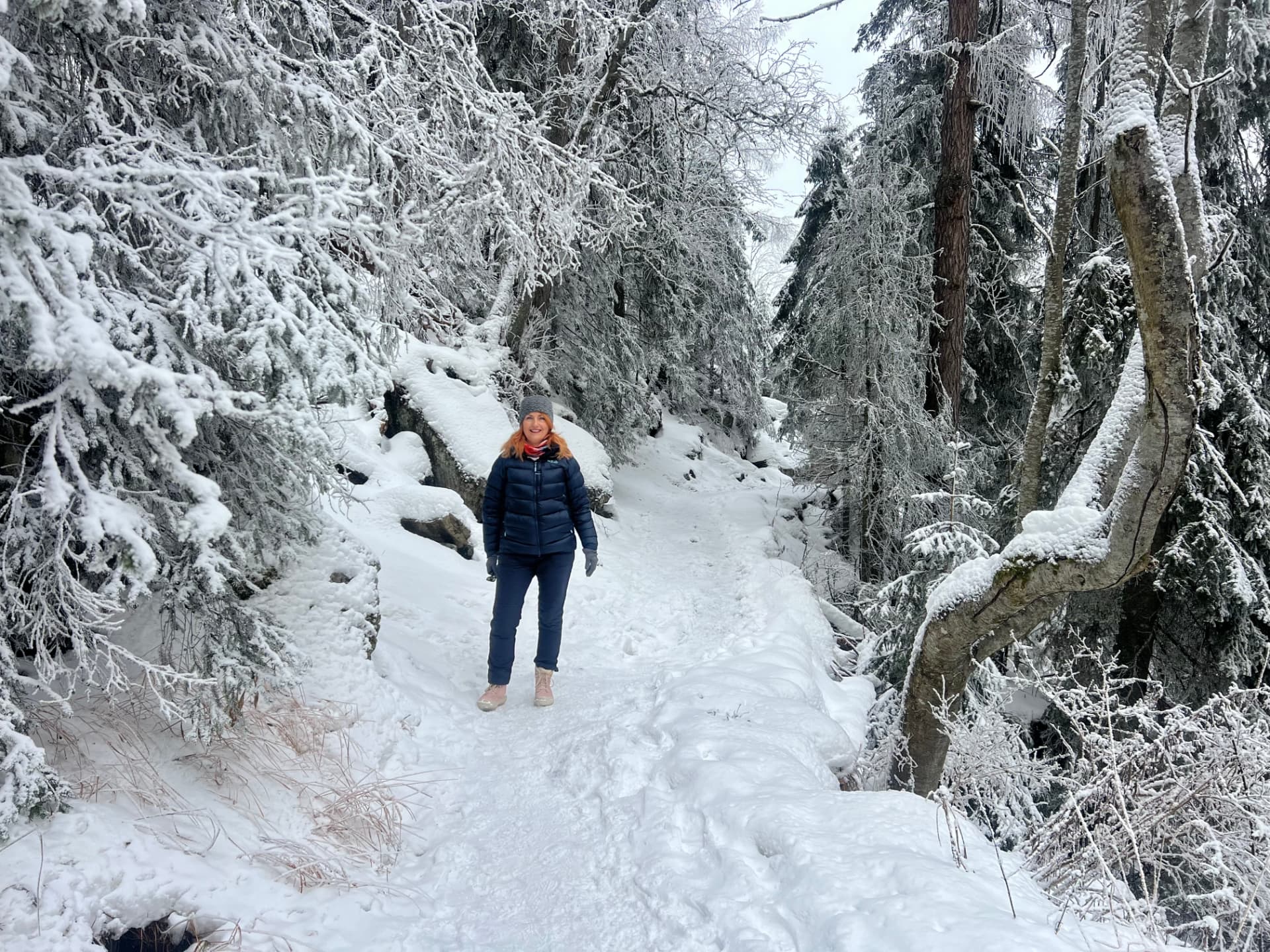 Julia walking a snowy path in the High Tatras in her blue jacket and pink boots