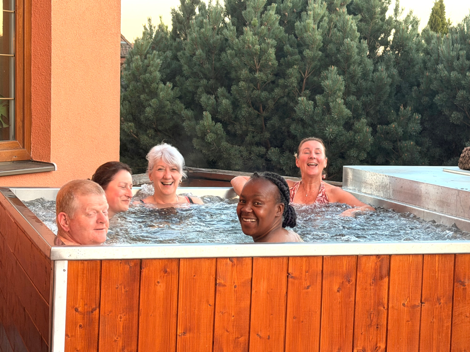 Retreat guests sharing a joyful moment in the outdoor jacuzzi at Edenium Chalet