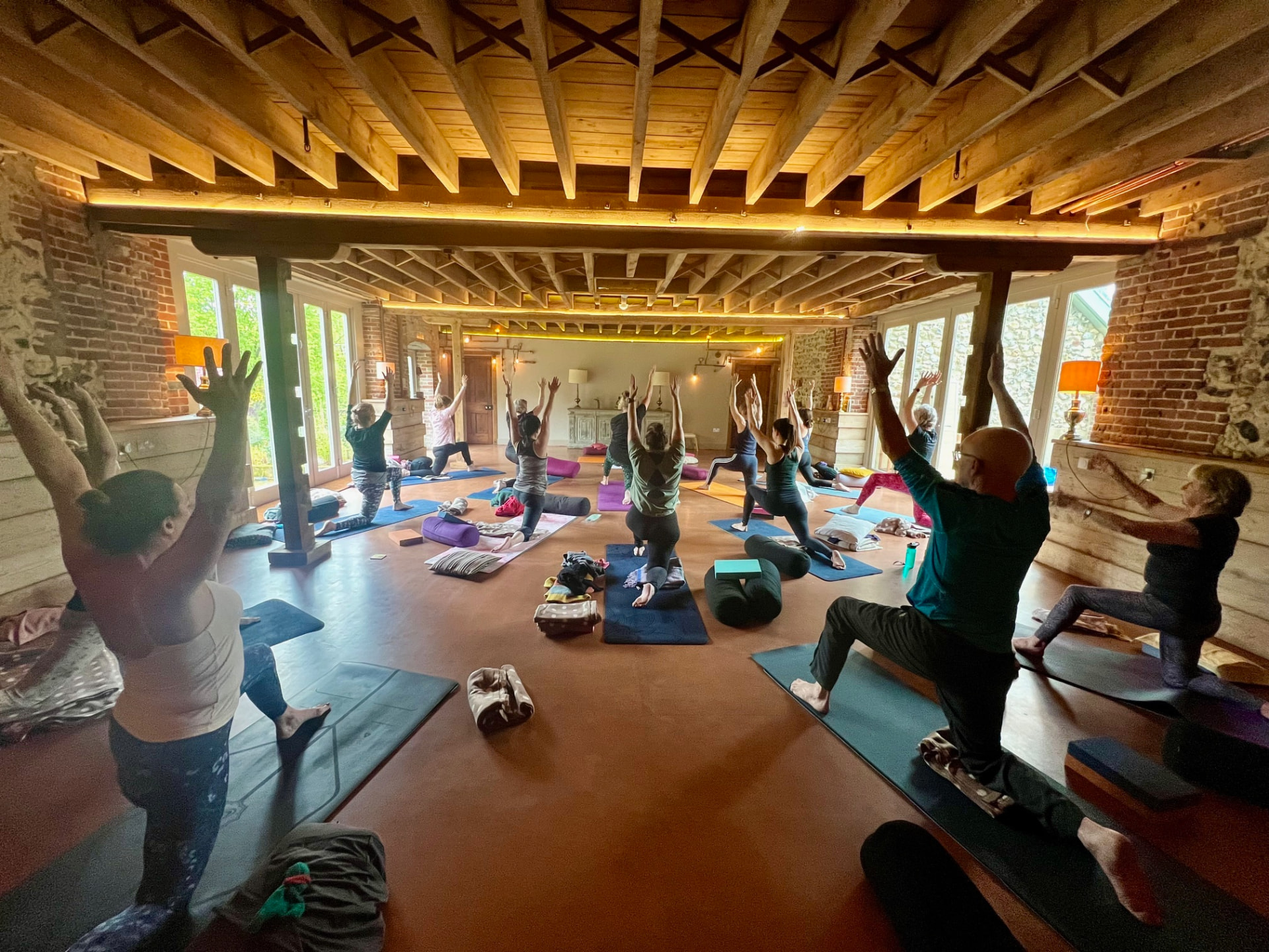 Group practising yoga in the timber-beamed barn at West Lexham