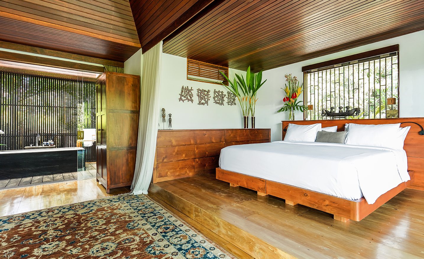 Open Balinese bedroom with hardwood floors and jungle bathing room