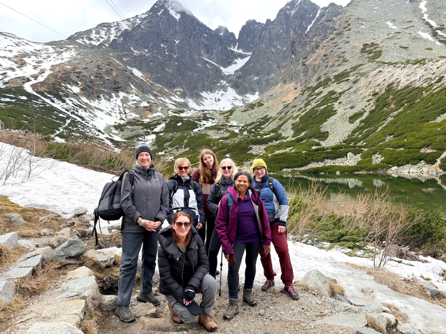 Smiling group of retreat women in front of a High Tatras mountain lake at Skalnaté pleso