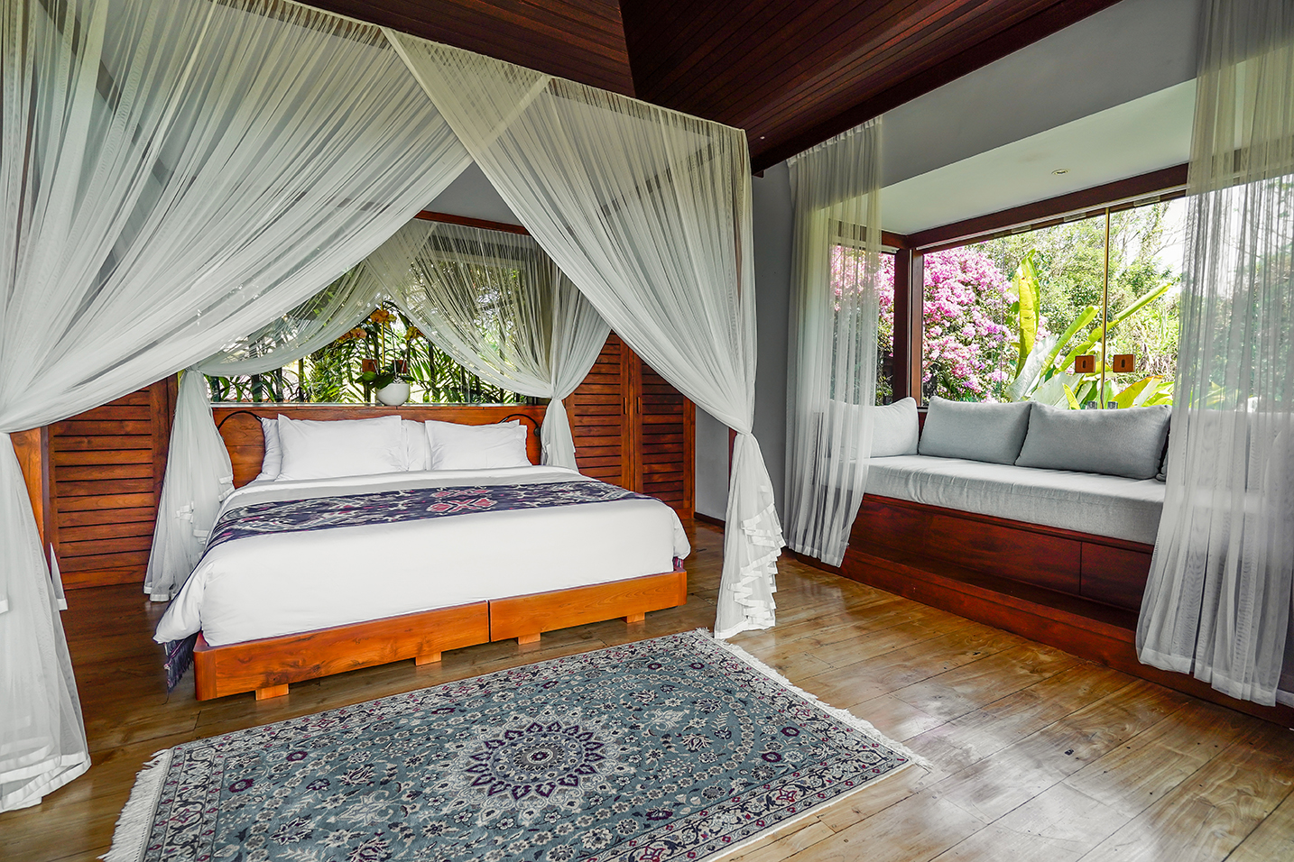 Bedroom with traditional Balinese four-poster canopy and garden views